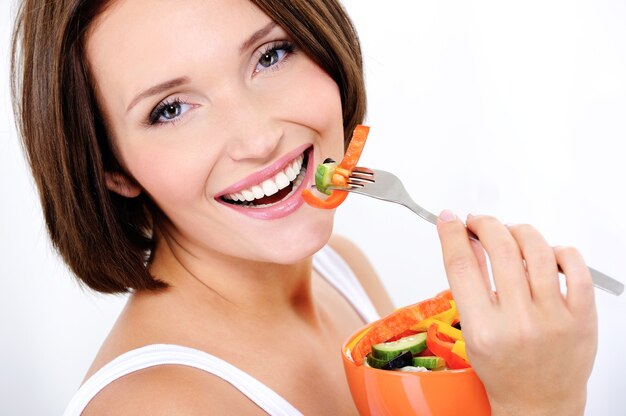 mulher feliz e atraente comendo salada de legumes