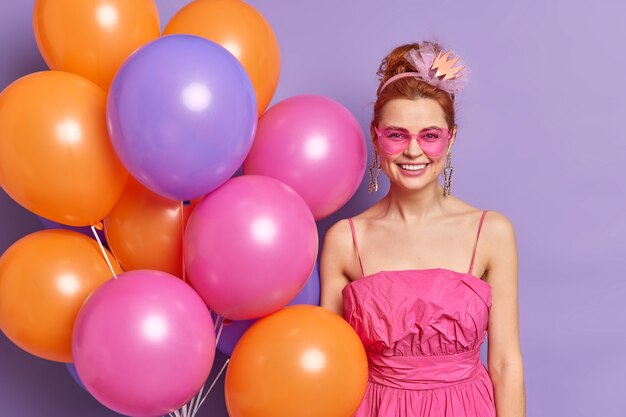 Mulher feliz e positiva na festa do Dia dos Namorados com balões multicoloridos vestidos com roupas de estilo retro e poses de acessórios