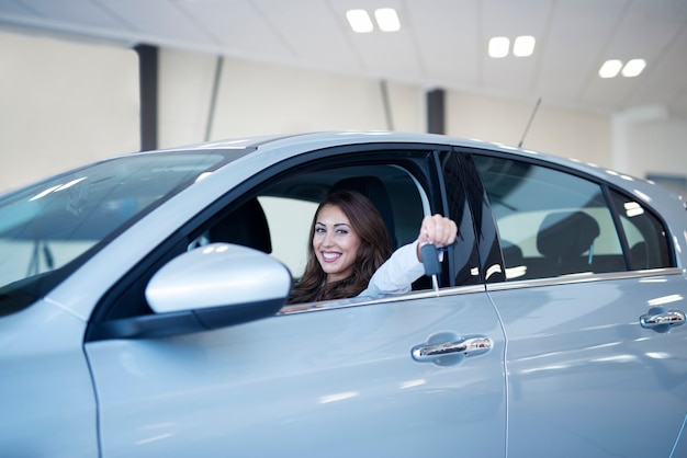 Mulher feliz e sorridente segurando as chaves de seu novo veículo