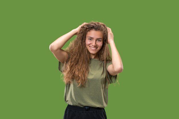 Mulher feliz em pé e sorrindo, isolado no fundo verde do estúdio.