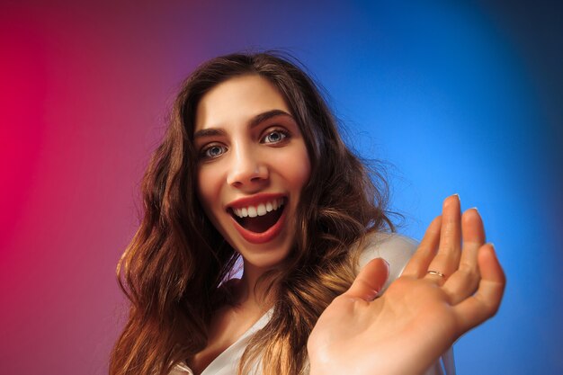 Mulher feliz em pé, sorrindo no fundo colorido do estúdio. Belo retrato feminino de meio corpo. Jovem satisfazer a mulher. Emoções humanas, conceito de expressão facial.