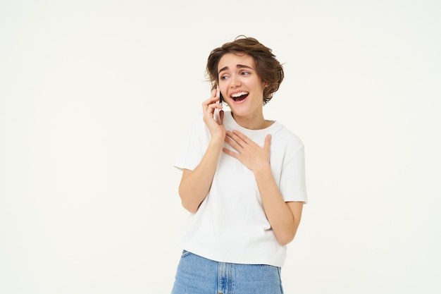 Mulher feliz falando casualmente no celular e sorrindo discutindo algo com um amigo durante o