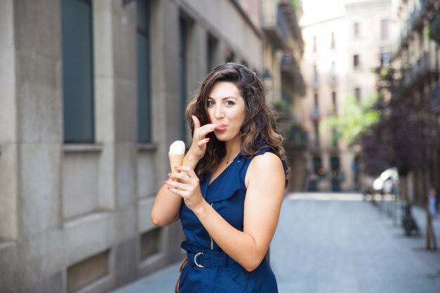 Mulher feliz lambendo o dedo enquanto come sorvete