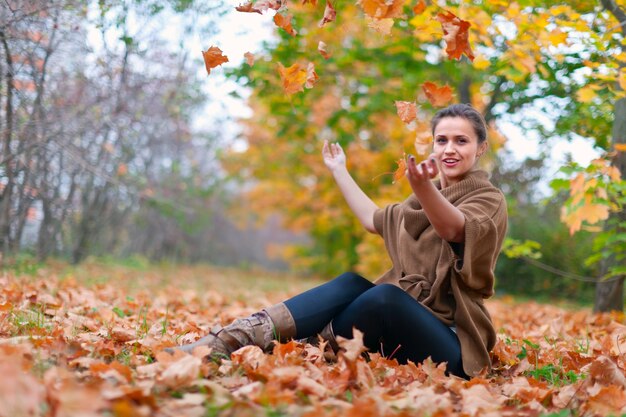 Mulher feliz lança folhas de outono