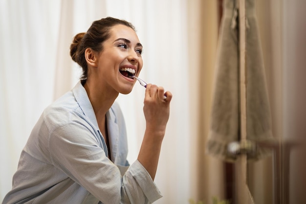 Mulher feliz limpando os dentes com uma escova de dentes pela manhã