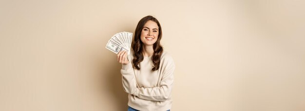 Mulher feliz mostrando dinheiro em dinheiro e sorrindo satisfeito conceito de microcrédito e compras em pé