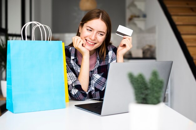 Mulher feliz, mostrando o cartão de crédito e olhando para laptop