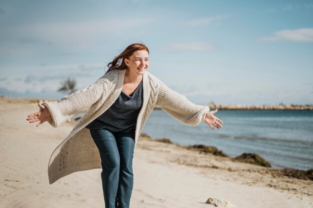 Mulher feliz na praia com tiro médio