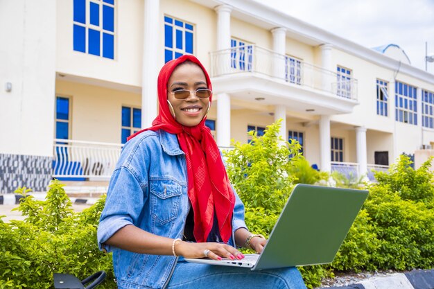 Mulher feliz navegando on-line usando um laptop enquanto está sentada em um parque