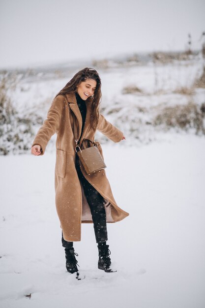 Mulher feliz no casaco no inverno lá fora no parque