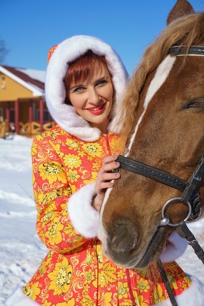 Mulher feliz no inverno com um cavalo na rua