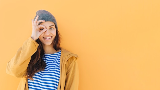 Foto grátis mulher feliz olhando através da mão binocular vestindo chapéu de malha