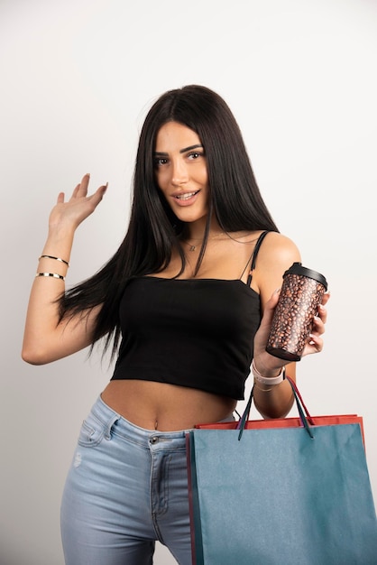 Mulher feliz posando com café e sacolas de compras. foto de alta qualidade