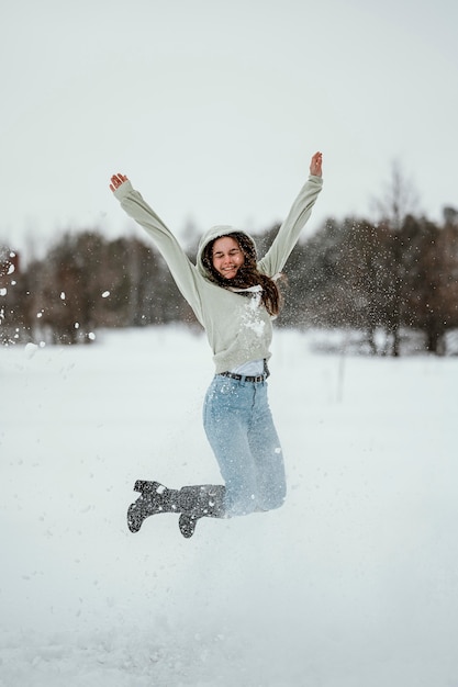 Foto grátis mulher feliz pulando ao ar livre no inverno