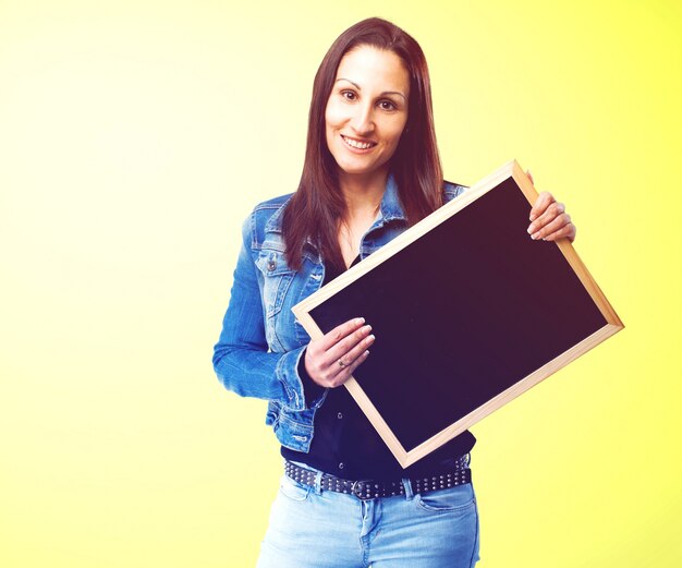 Mulher feliz que levanta com um pequeno quadro-negro