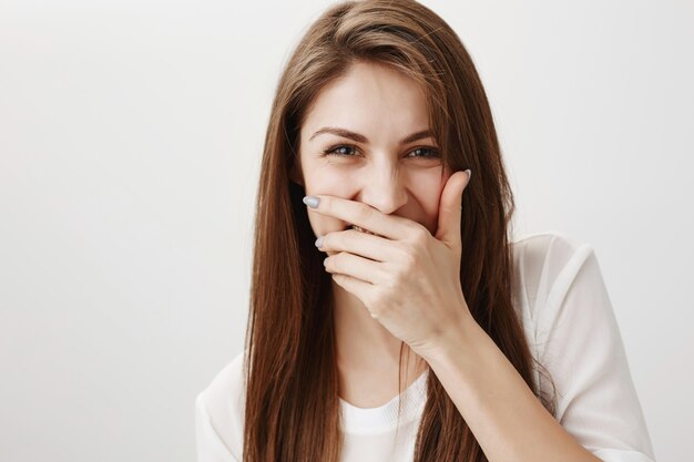 Mulher feliz rindo, tapando a boca com a mão e se divertindo