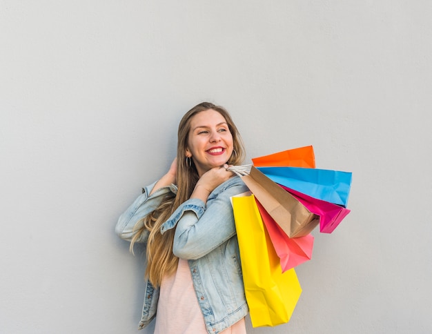 Foto grátis mulher feliz, segurando, bolsas para compras, atrás de, costas