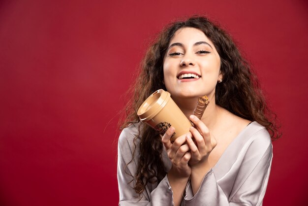 Mulher feliz segurando café e chocolate.