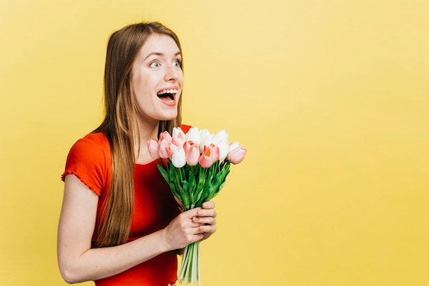 Foto grátis mulher feliz, segurando um buquê de tulipas com espaço de cópia