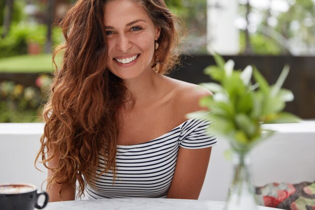 Mulher feliz sentada em uma cafeteria