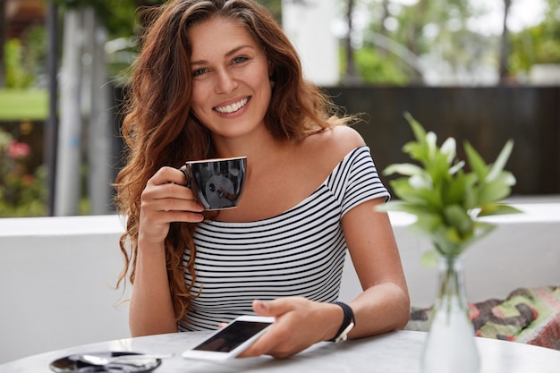 Foto grátis mulher feliz sentada em uma cafeteria