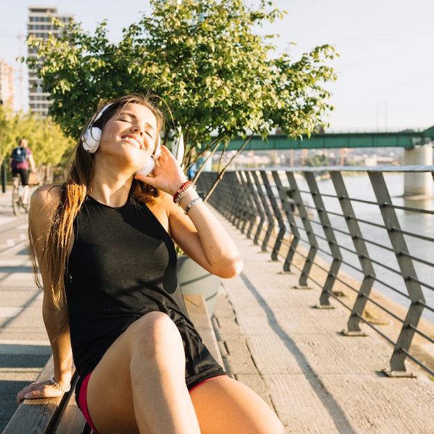 Foto grátis mulher feliz sentado no banco ouvindo música