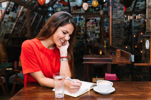 Mulher feliz, shelveule escrita, em, diário, com, xícara café, escrivaninha, em, caf�