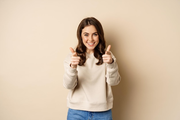 Mulher feliz sorridente escolhendo você apontando os dedos para a câmera e rindo convidando as pessoas em pé...