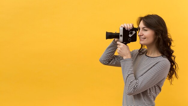 Mulher filmando com uma câmera retro