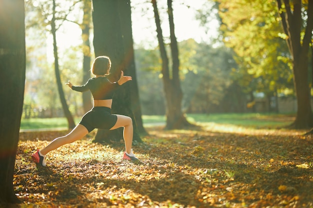 Mulher fitness esticando as pernas durante um dia de sol no parque