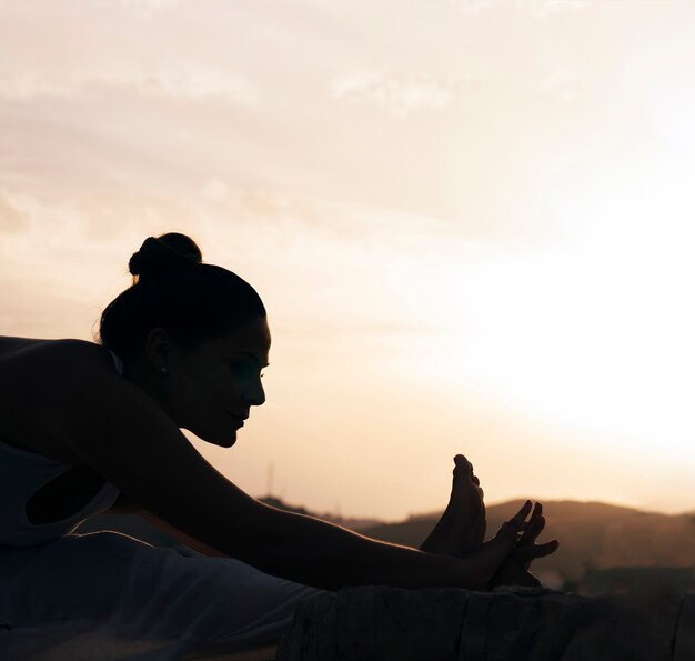 Mulher flexível fazendo yoga nas sombras