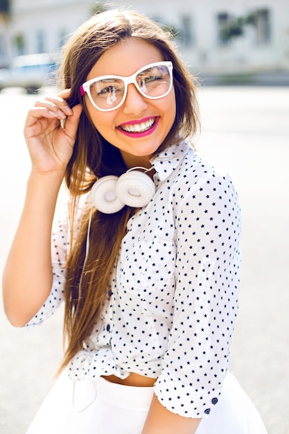 Foto grátis mulher fofa se divertindo na rua, usando vestido branco engraçado e fones de ouvido brancos