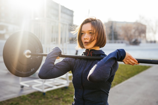 Foto grátis mulher forte, exercitando-se com peso. linda garota se preparando para um treino de levantamento de peso. esportes, conceito de fitness.