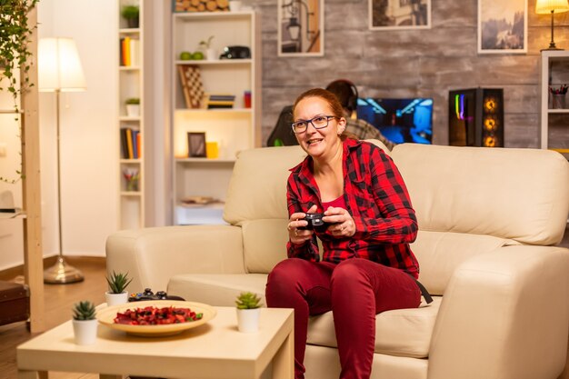 Mulher gamer jogando videogame no console da sala de estar tarde da noite