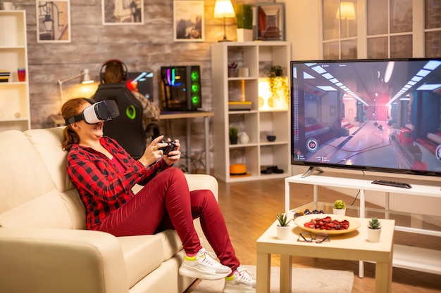 Mulher gamer jogando videogame usando um headset de rv tarde da noite na sala de estar