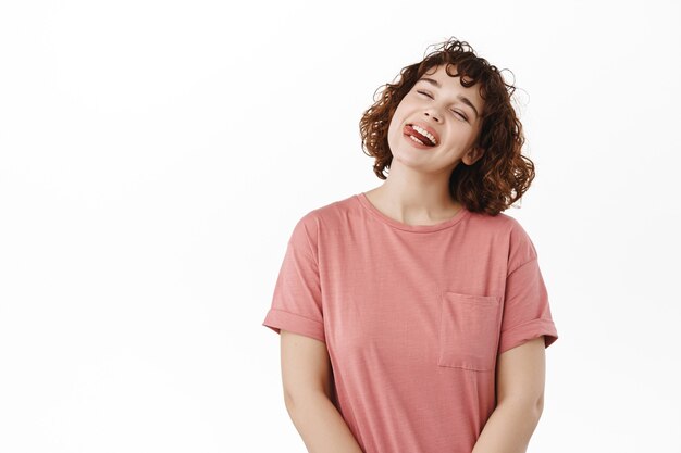 mulher, garota mostra sorrisos e risos de língua, inclina a cabeça despreocupada, aproveite as férias de verão, positivo em branco.