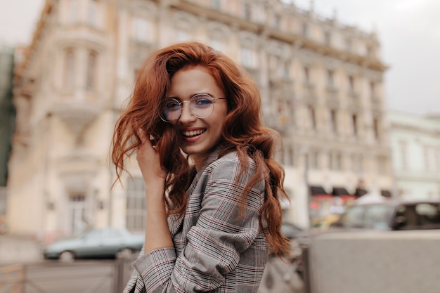 Foto grátis mulher gengibre em jaqueta cinza xadrez sorrindo do lado de fora