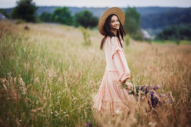 Mulher gira com buquê de lavanda no campo verde