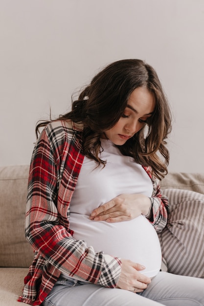 Mulher grávida atraente olha e toca suavemente a barriga