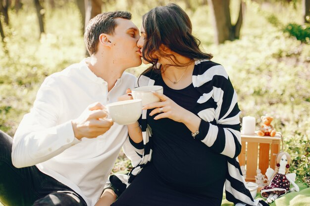 mulher grávida brilhante e feliz sentado no parque com o marido e beber um chá