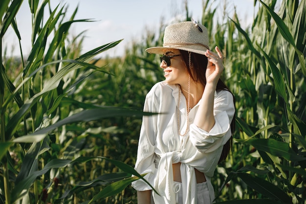 Foto grátis mulher grávida caminhando em um campo de milho. mulher morena caminhando em um campo de verão vestindo roupas brancas