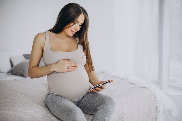 Mulher grávida com foto de ultrassom sentada na cama