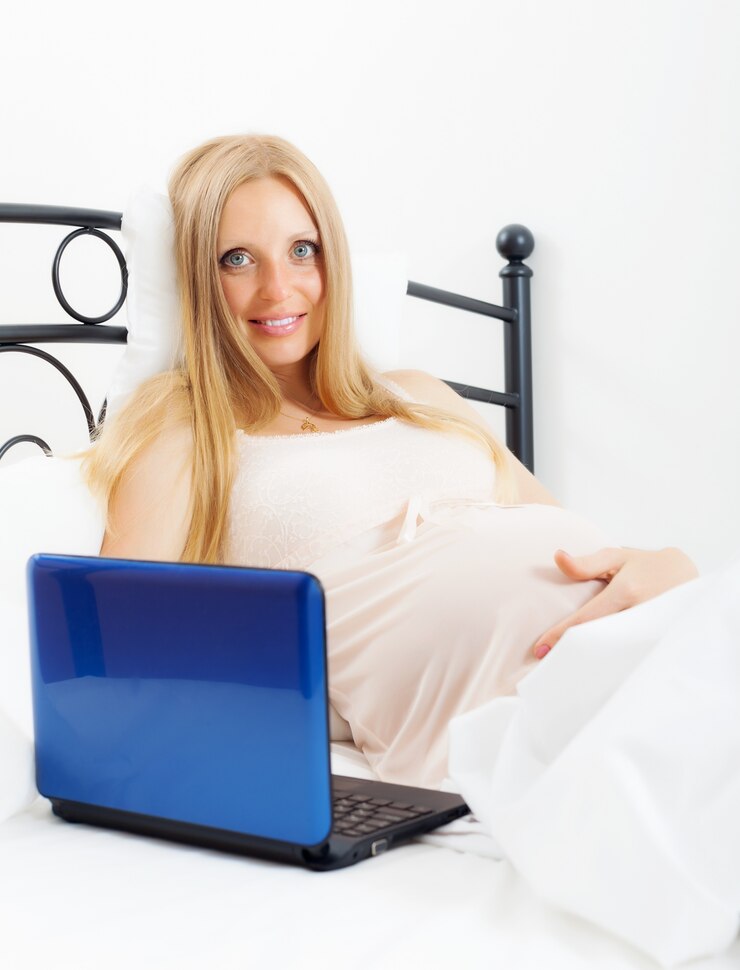 Foto grátis mulher grávida com laptop na cama