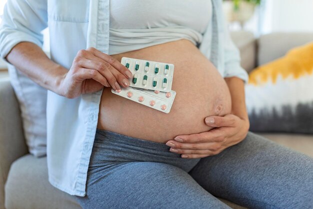 Mulher grávida com pílulas na mão remédio durante a gravidez barriga da mulher grávida e pílulas de vitamina na mão