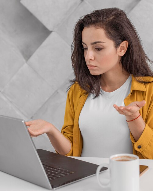 Mulher grávida confusa trabalhando em casa com um laptop