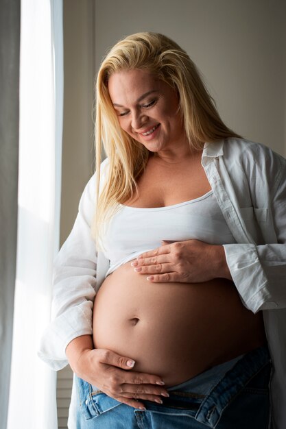 Mulher grávida de tamanho médio a passar tempo dentro de casa.