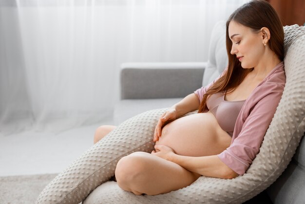 Mulher grávida de tiro completo no travesseiro de amamentação