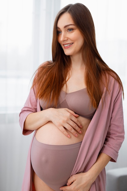 Mulher grávida de tiro médio posando em casa