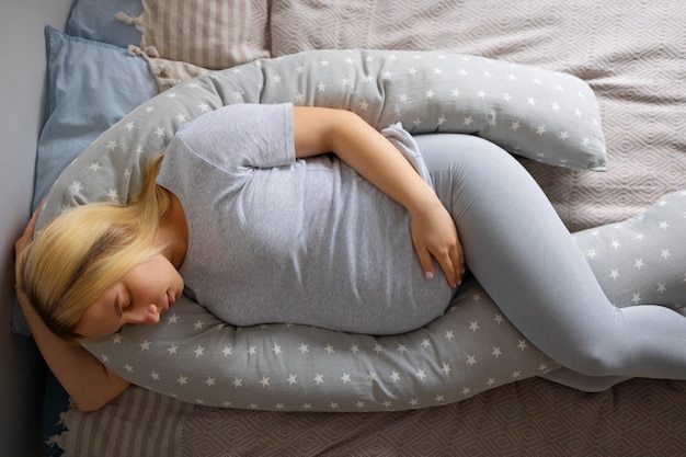 Mulher grávida de vista superior usando travesseiro de amamentação