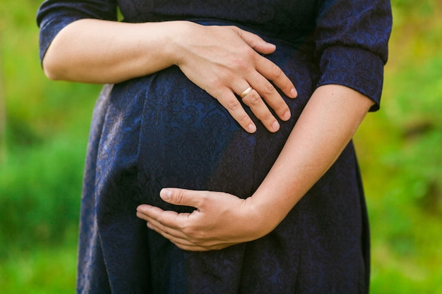 Foto grátis mulher grávida em vestido preto no fundo da grama verde manchada